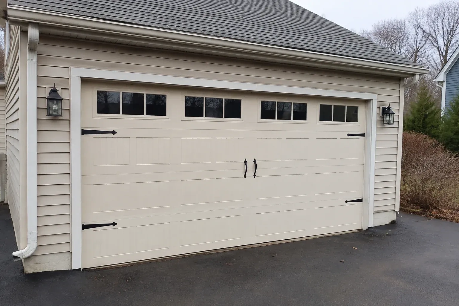 Cream carriage-house-style garage door with dark decorative hardware. — Carriage-House Garage Door Installation, New Tecumseth