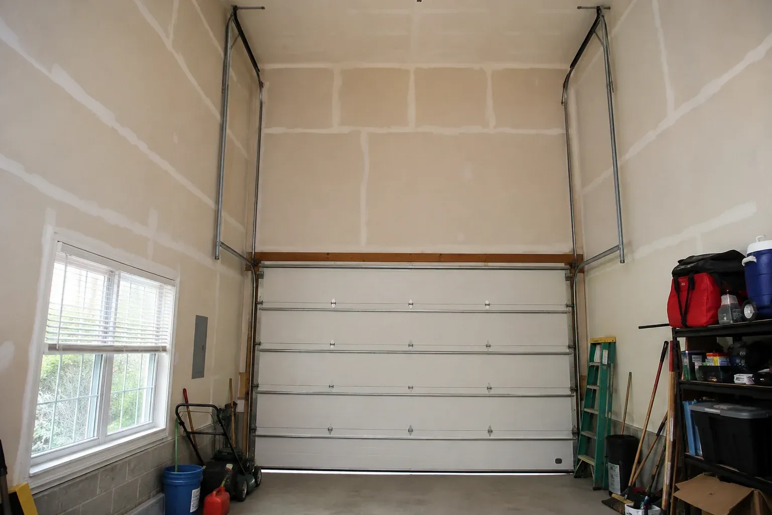 Tall garage interior with a sectional door and tracks extending into overhead space. — High-Lift Garage Door Conversion, New Tecumseth